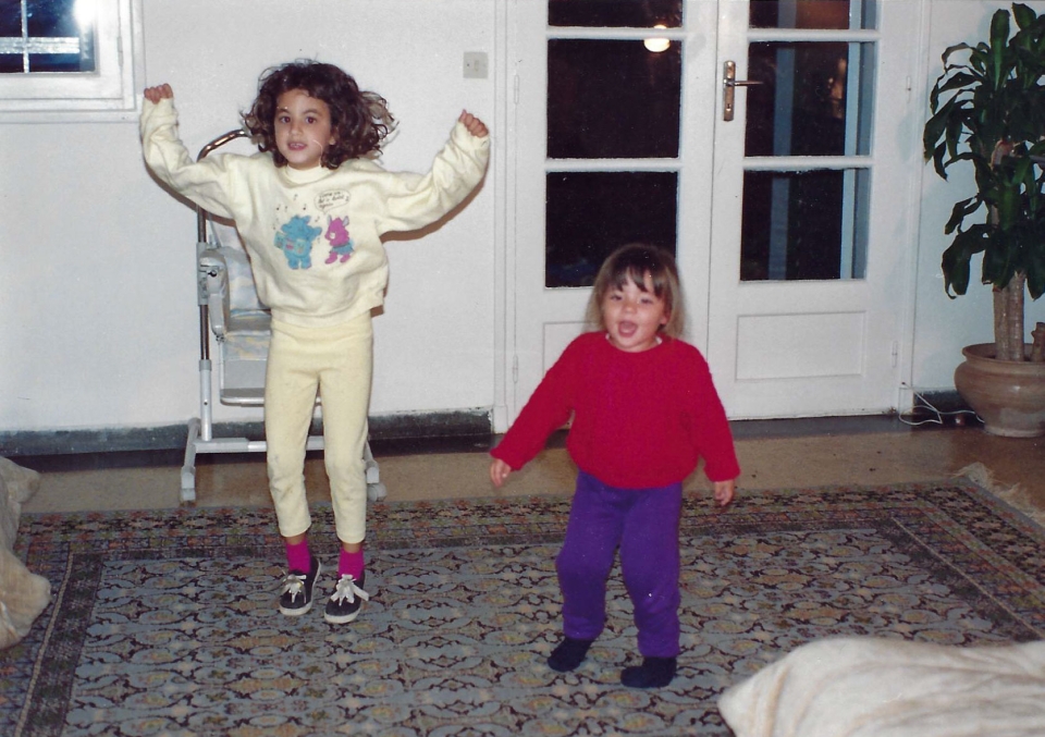 Je me souviens de ce moment comme si c'était hier. Jihane, ma petite en rouge, pleine de joie et d’énergie, dansait avec une insouciance qui remplissait toute la pièce. Ses rires résonnaient, et elle semblait tout simplement heureuse de partager ce moment avec sa grande sœur. À côté d’elle, Fatine, toujours la plus calme et concentrée, dans son ensemble jaune, prenait ce "concours de danse" très au sérieux, comme elle le faisait pour tout.Les voir ainsi, si proches, si heureuses, c'était un pur bonheur pour moi en tant que père. Elles étaient unies dans ces instants simples, leurs sourires et leur complicité illuminaient la maison. Ces moments, capturés sur cette photo, sont des souvenirs précieux qui me réchauffent le cœur. Jihane, toujours pleine de vie et d’amour, et Fatine, attentive et protectrice… elles étaient déjà inséparables.Aujourd'hui, en regardant cette photo, je ressens une douce nostalgie. Ce concours de danse, qui n'était qu'un jeu d'enfants à l'époque, est devenu l'un de mes plus beaux souvenirs.